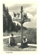 Wegweiser im Schwarzwald, darunter zwei in Trachten gekleidete Frauen