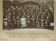 Teilnehmer (ca. sechsunddreissig Personen) am Lehrkurs der Infanterie-Schiessschule Spandau vor Waldhütte teils stehend, teils sitzend